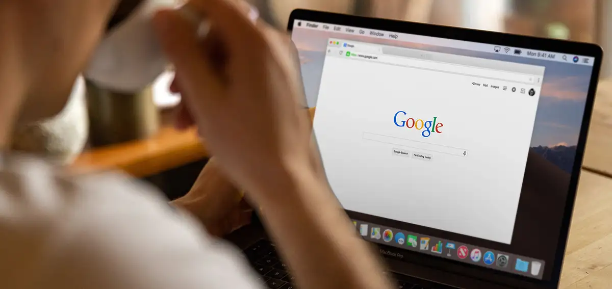 Person drinking tea and using Google from laptop