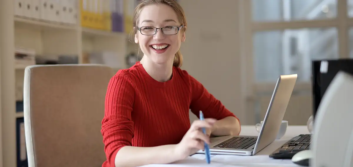 Young female smiling as she sits in front of laptop