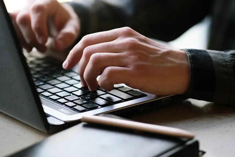 Hands typing on a laptop computer
