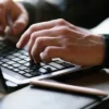 Hands typing on a laptop computer